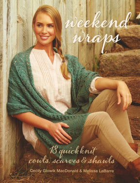 A woman sits against a rustic wooden fence, dressed in a teal knit wrap over a white blouse and beige pants. She smiles while looking to the side. Text on the image reads "Weekend Wraps: chic cowls, scarves & shawls" by Cecily Glowik MacDonald & Melissa LaBarre, published by Ingram Content.