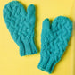 A pair of bright turquoise Knit Mitts from Ingram Content, featuring a textured pattern and ribbed cuff design, are showcased on a vibrant yellow background. Crafted by a knitting expert, these mittens have a thick, cozy appearance.