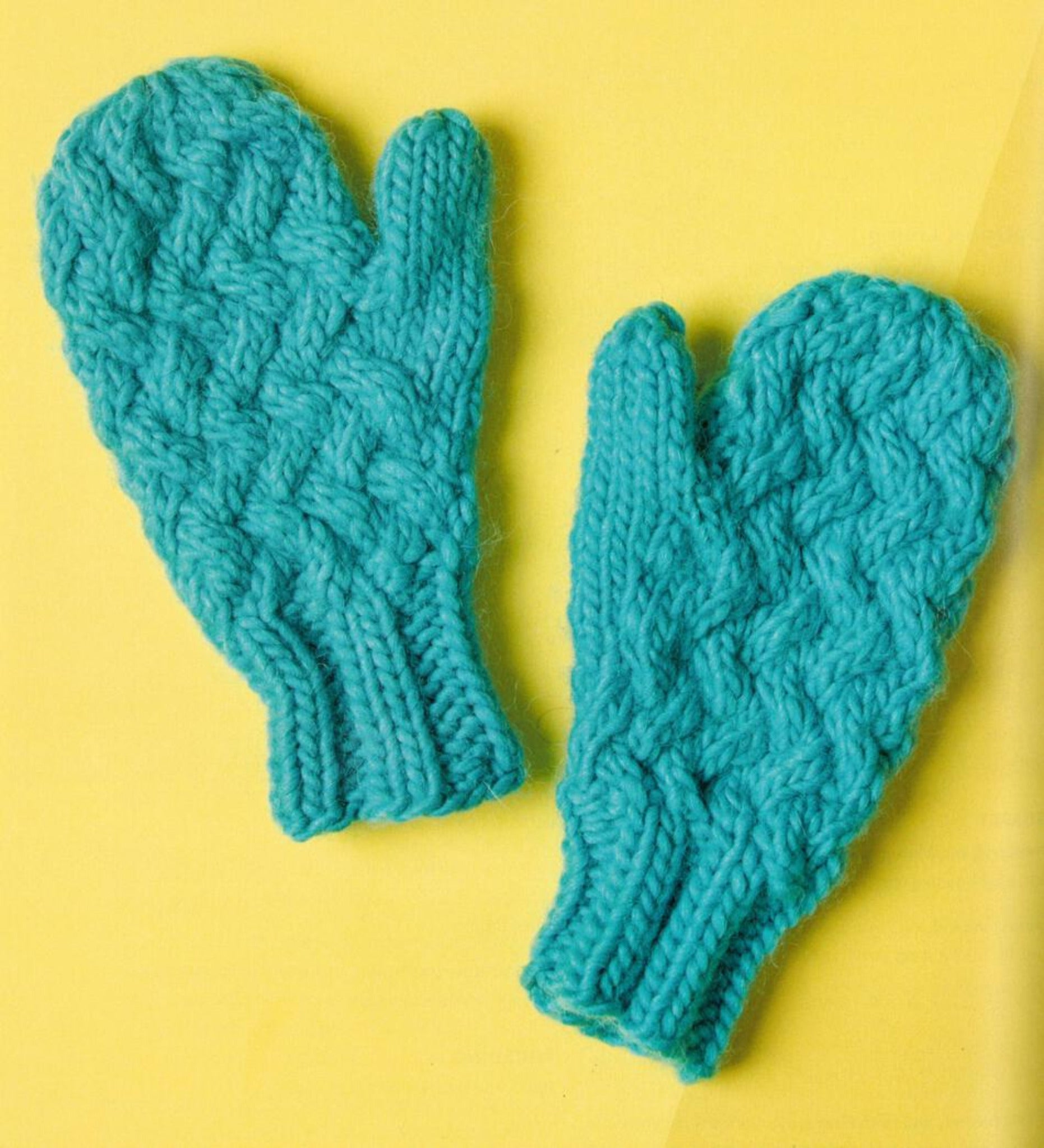 A pair of bright turquoise Knit Mitts from Ingram Content, featuring a textured pattern and ribbed cuff design, are showcased on a vibrant yellow background. Crafted by a knitting expert, these mittens have a thick, cozy appearance.