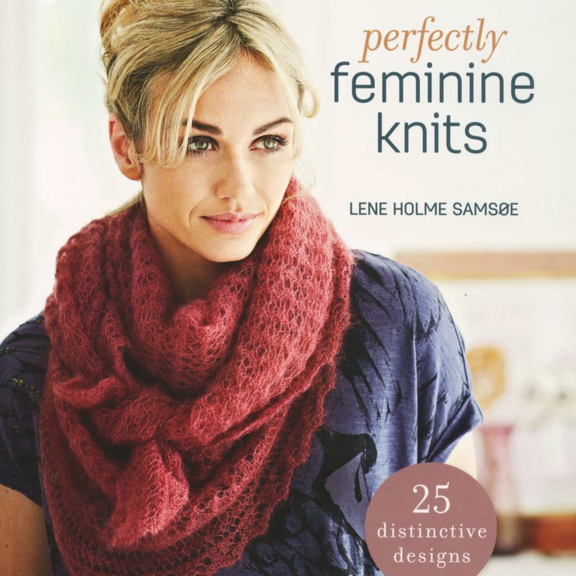 A woman with blonde hair is wearing a cozy, textured pink scarf over a patterned purple top on the cover of "Perfectly Feminine Knits" by Lene Holme Samsøe, branded by Ingram Content. Embracing delicate femininity, this book showcases "25 distinctive designs" as highlighted in a circular badge on the front.