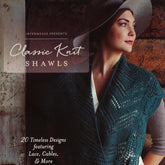 A woman wearing a blue, intricately knit shawl and a wide-brimmed hat stands in front of a rustic wooden wall, looking off to the side. Text on the image reads "Ingram Content Presents Classic Knit Shawls" and "20 Timeless Designs for the modern knitter featuring intricate lace, cables, & more.