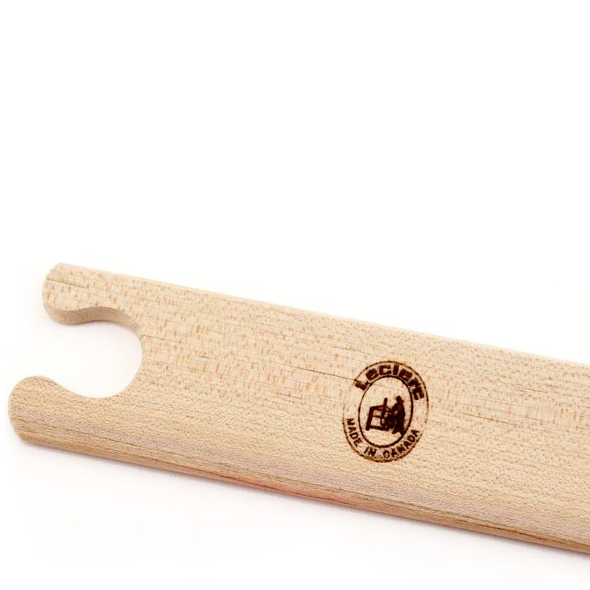 A Leclerc Stick Shuttle by Leclerc Looms, crafted from light-colored wood, prominently displays a "Made in Canada" stamp and logo near one end. This end features a U-shaped notch for holding yarn, similar to those found on robust shuttles. The background is plain white.