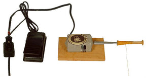 The image shows the Leclerc Electric Bobbin Winder, Single Ended, from Leclerc Looms. The device features a metal body mounted on a wooden base and includes a wooden handle at one end. A black cable attaches to a foot pedal, which is used to operate the bobbin winder.