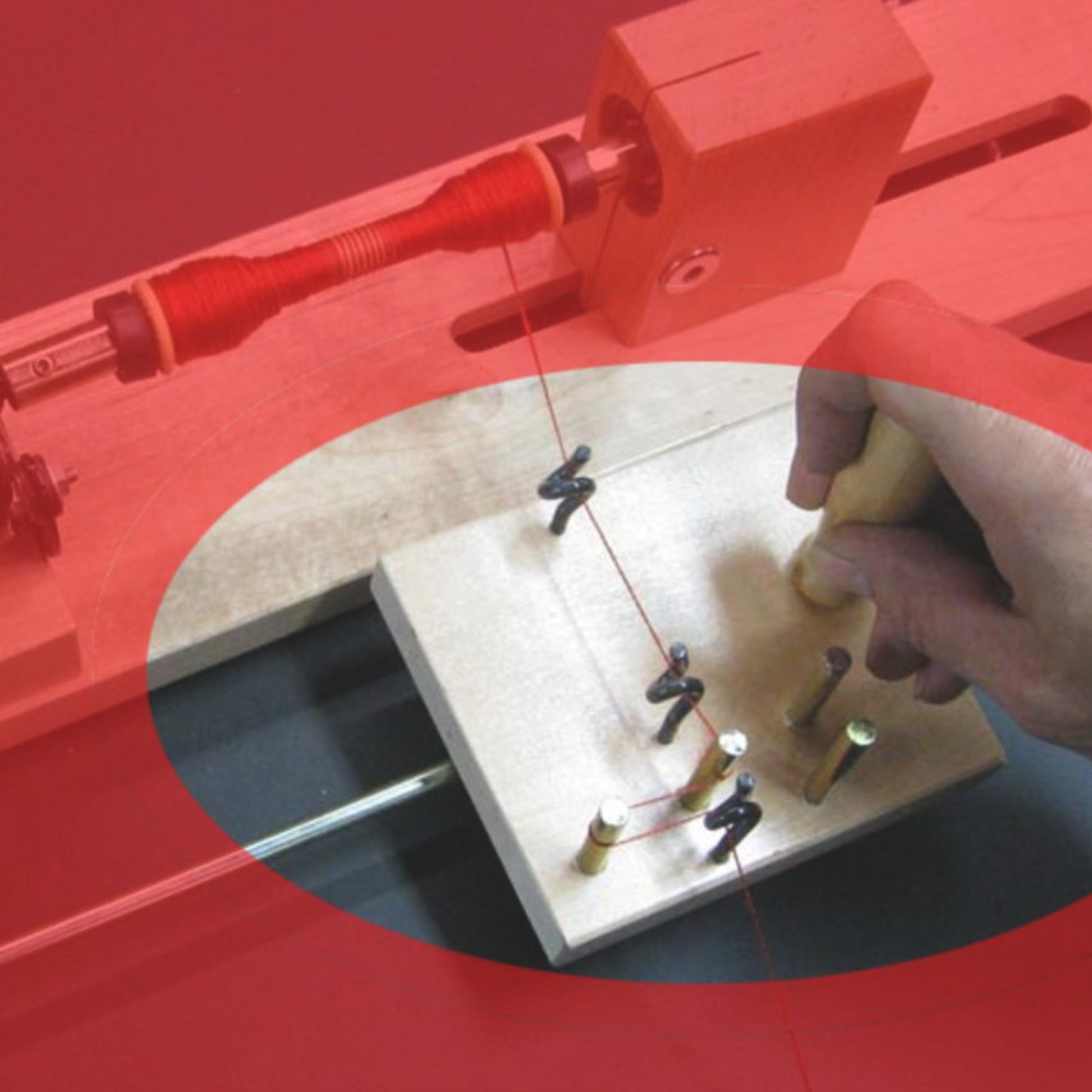 A hand is adjusting a spool of red thread on a small wooden device, equipped with several pegs and clips, which appears to be part of the Leclerc Tension Device Kit for Electric Winders by Leclerc Looms. The setup is likely used to wind perfect bobbins for crafting. The image features a red overlay.