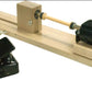 The Leclerc Looms Electric Bobbin Winder, Single Ended, features a sleek black electric motor on the right, mounted on a sturdy wooden frame with a central spindle. The motor's speed is easily controlled via a wired black foot pedal controller positioned to the left.