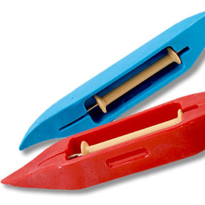 The image displays two Leclerc Budget Shuttles by Leclerc Looms, one in blue and one in red, used for textile weaving. Each high-density plastic shuttle features an internal spindle for yarn storage. The shuttles are positioned at an angle, with the cost-effective red shuttle at the bottom and the blue shuttle on top, making them ideal for beginner weavers.