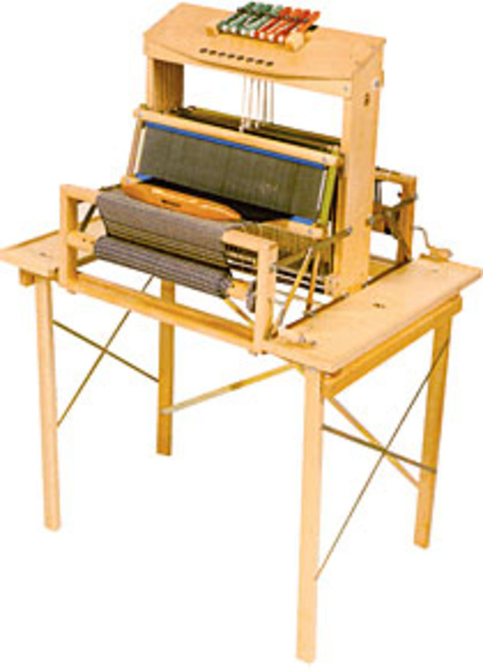 The Leclerc Table Loom Stand for Dorothy or Voyageur is a versatile wooden tabletop loom available in 4 or 8 shaft variants, ideal for handcrafting textiles and fabrics. It features multiple colored threads and intricate weaving mechanisms, supported by a sturdy wooden frame with aligned strings and gears. Additionally, the loom includes convenient side shelves for tool storage but does not come with treadles.