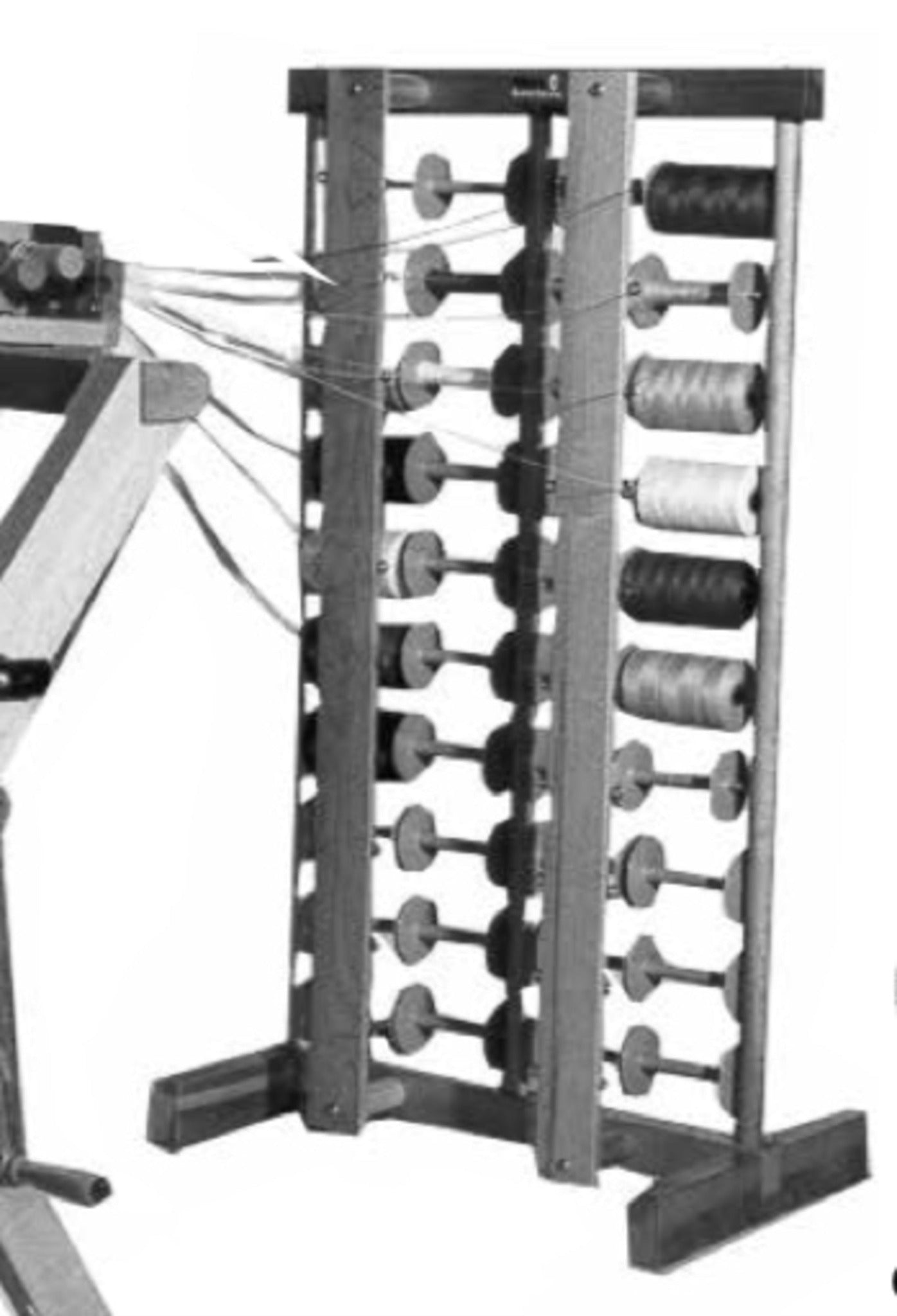 A black and white image features a Leclerc Thread Guide by Leclerc Looms, standing tall with two sturdy legs and holding multiple spools of thread. Each guide connects the spools to wires extending to the left, suggesting it is part of a textile or weaving machine.