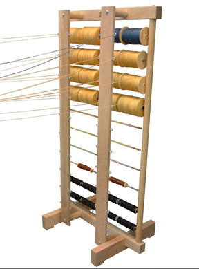 The Leclerc Thread Guide from Leclerc Looms is a wooden yarn rack that holds multiple spools of thread in various colors, neatly organized in rows. Featuring two vertical beams and several horizontal rods for easy placement, the threads unwind smoothly thanks to the thread guide, making it perfect for efficient warping with yarn. The rack stands securely on a sturdy base.