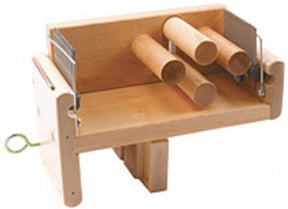 The Leclerc Tension Box by Leclerc Looms is a wooden setup featuring mounted cylindrical rods and vertical guides designed for precise angled cutting. It includes adjustable sections and a clamp for holding materials securely in place, ensuring the same level of precision in sectional warping as the renowned Leclerc loom.