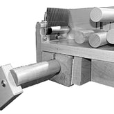 Black and white image showing a woodworking tool or jig. The apparatus includes cylindrical wooden rods and squared beams, possibly for cutting or shaping wood. One cylindrical rod is prominently inserted into a square wooden bracket, reminiscent of the sturdy constructions seen in the Leclerc Tension Box Adapter for Compact and Similar Looms by Leclerc Looms.