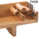 The Leclerc Tension Box Comb by Leclerc Looms is a wooden weaving accessory with multiple cylindrical rods and a 4 dent comb attachment. The comb, located on the right side of the device, is designed for guiding or organizing threads or materials. The structure is mounted on a small wooden base, characteristic of a Leclerc Tension Box.