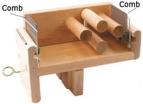 The Leclerc Tension Box Comb by Leclerc Looms is a wooden drum carder featuring two labeled components called "Comb" on the sides. It includes three horizontally positioned wooden rollers in the middle, serving as a weaving accessory to align and blend fibers for spinning, similar to its counterpart, the Leclerc Tension Box.