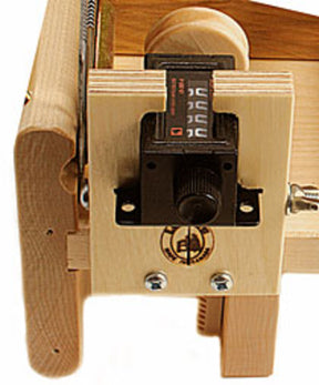 A close-up of the Leclerc Yardage Counter by Leclerc Looms, a finely constructed wooden knitting machine. It features visible screws, a rotating dial for adjustable knitting tension, and a manual row counter attached. The tension box ensures precise control, and the yardage counter displays numbers indicating the progress of rows completed.