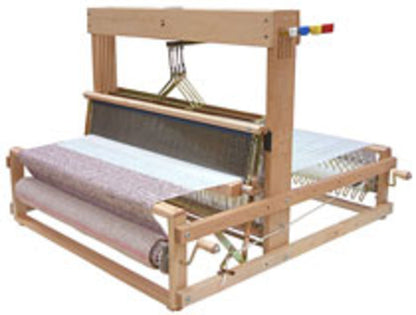 A tabletop weaving loom boasting multiple colored levers and beams, specifically designed for fabric textile creation, is partially adorned with woven fabric. The loom, identified as the Leclerc Dorothy Table Loom by Leclerc Looms, has threads intricately running through its various mechanisms.