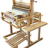 The Leclerc Table Loom Stand for Dorothy 24", featuring 4 shafts, side shelves, and 6 treadles, crafted from light-colored wood, is designed for convenient manual textile production with an adjustable loom stand.