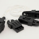 Four Leclerc Clip Temple accessories, made of black plastic with jagged teeth, are attached to a white cord and arranged on a plain white background. These innovative clips from Leclerc Looms feature a textured grip and an eyelet hole for secure attachment, making them ideal for use with Leclerc looms and other weaving projects.