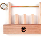 The Leclerc Shaft Stabilizer by Leclerc Looms is a wooden stand that features four vertically mounted wooden pegs and a metal rod across the top, perfect for holding circular items such as thread spools or napkin rings. The stand also showcases a logo featuring a sheep with text around it, evocative of traditional counter-balanced looms.