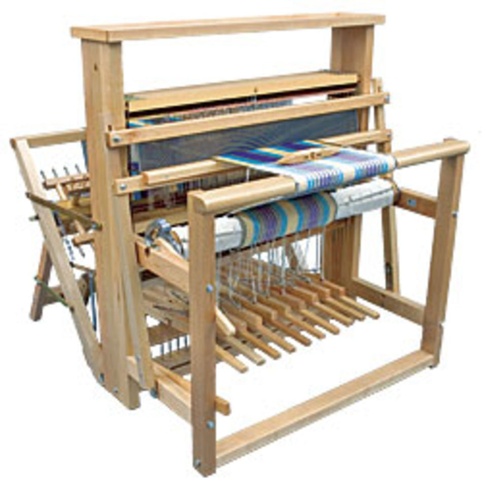 The Leclerc Nilus II 8-Shaft Floor Loom by Leclerc Looms is a wooden floor loom designed for weaving. It features multiple bars, beams, and pedals, with a partially woven, colorful fabric on it. The structure is made from light-colored wood and includes various metal and string components for adjusting tension and patterns.