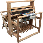 Image of the Leclerc Nilus 8-Shaft 10-Treadle (Back Hinged) Jack Floor Loom by Leclerc Looms, fully assembled with a partially woven colorful fabric in progress. The loom features multiple heddles, treadles, and a warp beam. The fabric displays a mix of stripes and patterns in various colors.