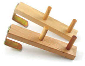 Two Leclerc Warping Pegs from Leclerc Looms, each featuring three cylindrical wooden pegs and metal brackets for mounting. The peg holders are arranged diagonally across each other on a white background.