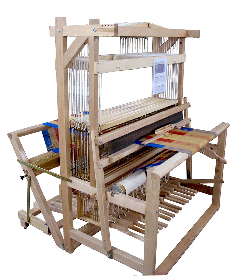 A Leclerc Colonial V2 Jack Floor Loom by Leclerc Looms with several components, strings, and levers. It has a partially woven colorful fabric with red, blue, yellow, and white patterns emerging from it. The loom appears to be in use, with yarns meticulously threaded through various parts.