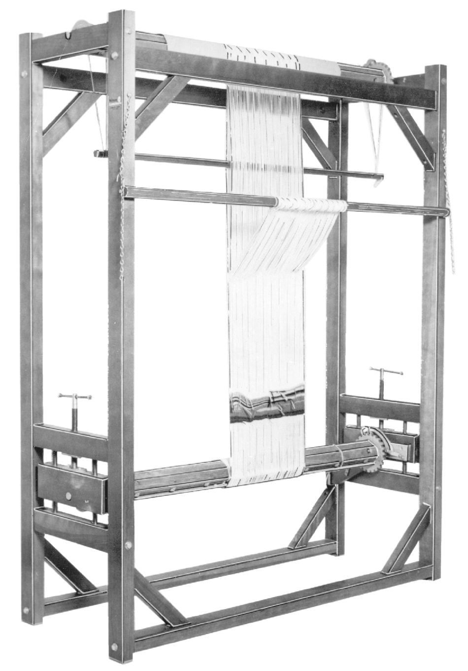 A black and white image features the Leclerc Gobelin Tapestry Loom by Leclerc Looms. The vintage upright loom is fitted with vertically arranged threads, indicative of its setup for traditional tapestry weaving. Its sturdy wooden frame includes several horizontal beams and cranks, typically used to tension the fabric.