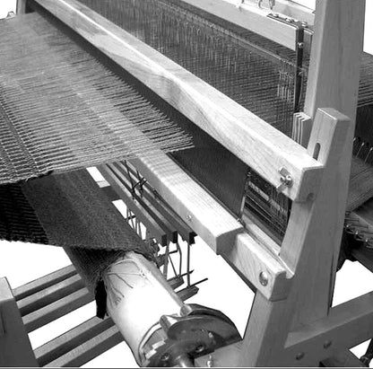 Black and white image of a close-up view of a traditional wooden Leclerc Batten Weighted Beater weaving machine by Leclerc Looms in action. The fabric is being woven tightly with the loom's intricate threads and pattern visible, along with various mechanical parts and levers.