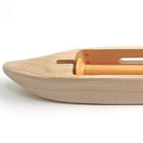 A detailed image of the Leclerc Double-Bobbin Boat Shuttle from Leclerc Looms, a boat-shaped tool commonly utilized in handweaving to efficiently carry the weft yarn back and forth between the warp threads. This shuttle features a smooth finish, an even tension system, and a cylindrical bobbin holder.