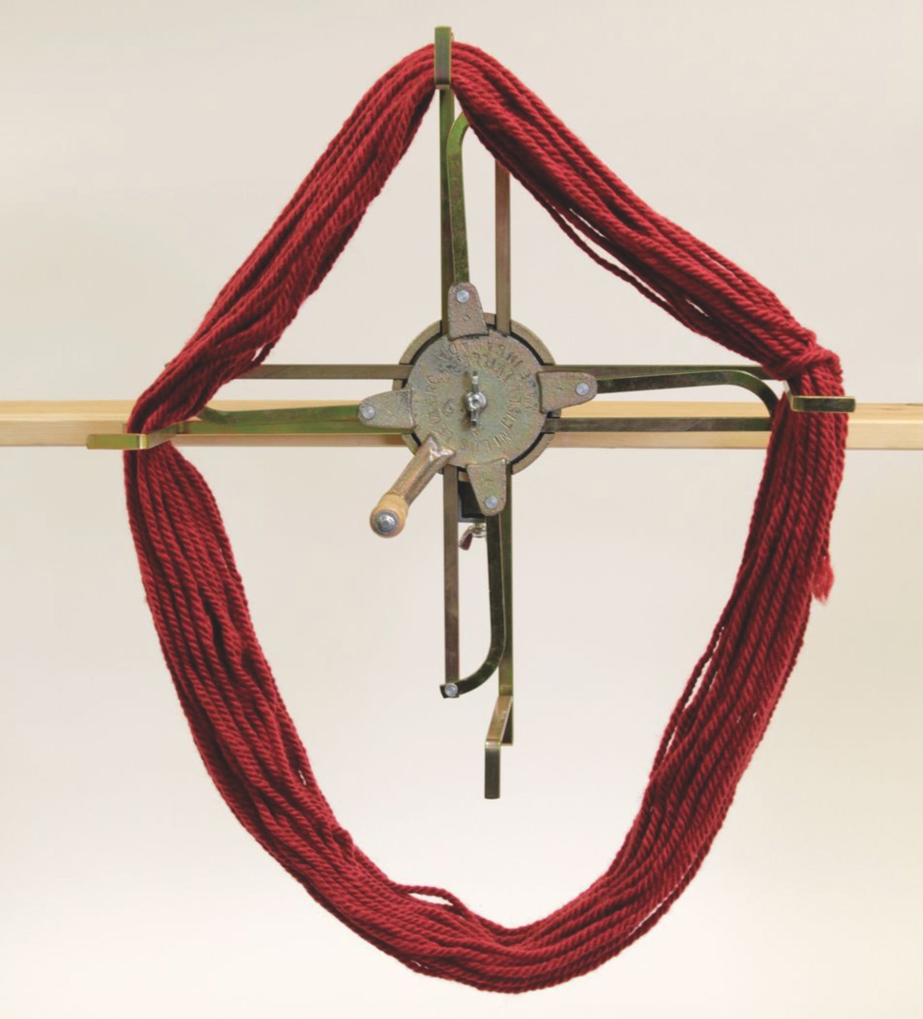 A Leclerc Looms Swift and Skein Winder loaded with a red hank of yarn. The yarn swift features an adjustable mechanism to hold and unwind the yarn smoothly. Positioned against a plain background, this setup is perfect for yarn winding or knitting.