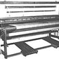 The black and white image showcases a Leclerc Kebec II 4-Shaft Floor Loom from Leclerc Looms. This old-fashioned weaving device features a complex assembly of frames, beams, rods, and a large fabric roll centrally positioned. It is designed for weaving textiles by interlacing threads either manually or mechanically.