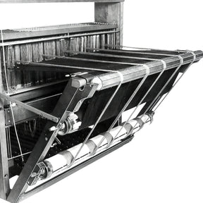 A black and white image of the Leclerc Double Warp Beam Artisat, an antique loom from Leclerc Looms, showcasing the intricate machinery and threads. The device features a double warp beam along with a series of wooden and metal parts, including rollers, levers, and strings likely used for weaving textiles.