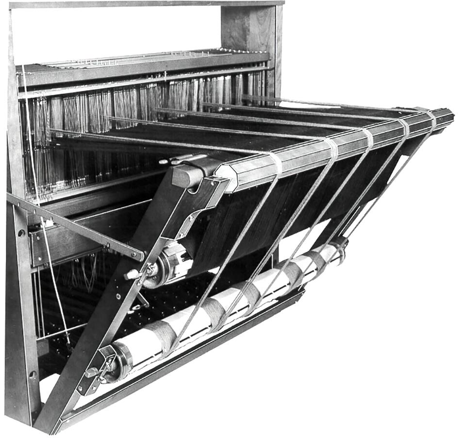 A black and white image of a vintage Leclerc Double Warp Beam Standard by Leclerc Looms. The loom is equipped with multiple threads and weaving components, including rollers and heddles. It appears to be set up for the weaving process, with threads neatly aligned and tensioned.