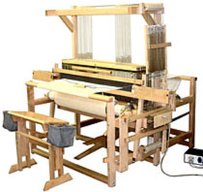 The Leclerc Weavebird V2 Floor Loom by Leclerc Looms is a large, wooden weaving loom equipped with foot pedals, multiple beams, and vertically arranged threads across the structure. The loom appears to be set up for fabric weaving and features various visible mechanical components to control the weaving process.