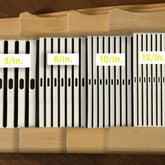 Kromski High-Quality Saw Blades Set: This versatile collection of metal-bodied blades, featuring dark cutouts, comes organized in a wooden holder and labeled by teeth per inch — "5/In.", "8/In.", "10/In.", and "12/In." These vertically arranged blades bring to mind the precise alignment of heddles in the renowned Kromski Rigid Heddle Reed designed for Harp Forte Looms by Kromski North America.