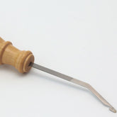 A Kromski North America Kromski Double Ended Rigid Heddle Hook, featuring a wooden handle and metal shaft, rests on a white surface. The tool's head resembles a rigid heddle hook with its flat, curved tip designed for precise insertion or removal tasks.