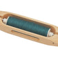 The Schacht Boat Shuttle by Schacht Spindle Co. features a smooth, elongated oval shape with a hollowed-out middle section that holds a spool of teal thread in the center.