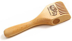 The Schacht Weighted Tapestry Beater by Schacht Spindle Co. is a light wooden kitchen utensil blending the features of a spatula and a fork, meticulously designed to serve as a sculpted beater. Its handle gracefully tapers into a broader, flat end adorned with multiple vertical slits, featuring an engraving of a group of people and text on the flat surface.