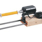 The Schacht Double-Ended Electric Winder by Schacht Spindle Co. is shown. This device, featuring an electric motor and foot pedal, securely holds a yellow thread spool in position on a wooden base supported by two metal rods, providing hands-free operation for crafting fishing flies.