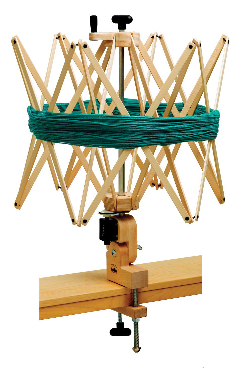 A Schacht Ultra Umbrella Swift by Schacht Spindle Co. holds a teal skein of yarn. The adjustable swift is clamped to the edge of a wooden table and features an expandable frame to accommodate different sizes of skeins up to 93 inches.