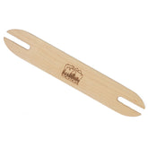 The Schacht Stick Shuttle by Schacht Spindle Co. boasts a slim profile and rounded ends, with an engraved logo in the center. Its smooth oiled finish enhances its elegance, similar to renowned wooden weaving shuttles, set against a white background.