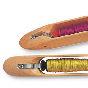 Two Schacht End Delivery Shuttles from Schacht Spindle Co. for weaving are shown. The top shuttle holds purple yarn, while the bottom shuttle holds yellow-green yarn. Each shuttle is designed to hold a bobbin of thread, such as Schacht Pirns, enabling the yarn to be fed smoothly and with even tension during the weaving process.