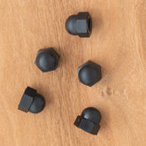 Five Schacht Ladybug Lazy Kate Cap Nuts from Schacht Spindle Co. are scattered on a wooden surface.