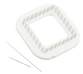 A Schacht Zoom Loom 4" x 4" from Schacht Spindle Co. is a white square object with rounded corners and parallel diagonal grooves along its edges. Beside it, there are two thin needles positioned parallel to each other on a white background, resembling tools from the weaving kit.