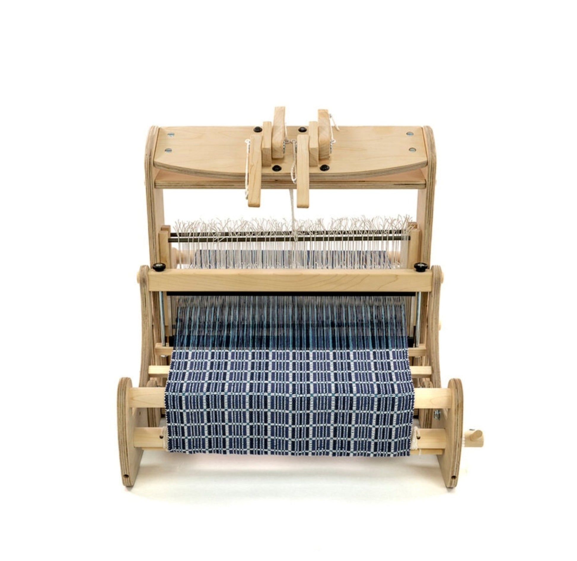 A Schacht Cricket 15" Quartet from Schacht Spindle Co. features a partially woven fabric in a blue and white checkered pattern. The setup is minimal, highlighting the loom's various components such as warp threads, heddles, and reed as they work together on this weaving project.