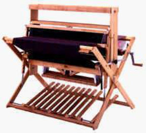 The Schacht Wolf Loom, 4 Later Add on Kit by Schacht Spindle Co. is a wooden handloom weaving machine featuring a rectangular frame and essential components like a warp beam, heddles, and reed. It includes a crank handle on one side and is designed for small-scale weaving projects, making it perfect for weaving enthusiasts.