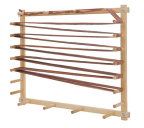 The Schacht Warping Board by Schacht Spindle Co. is expertly crafted from hard maple, featuring robust, horizontally arranged pegs ideal for measuring and winding yarn. The yarn is threaded in a zigzag pattern around the pegs, making it both functional and elegant against a plain white background.