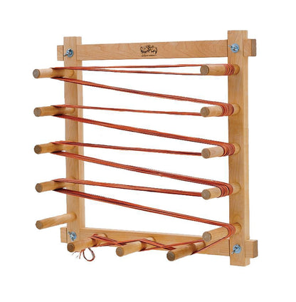 A Schacht Warping Board by Schacht Spindle Co., crafted from hard maple, is displayed holding several strands of reddish-brown yarn wrapped in a zigzag pattern. The freestanding design features durable horizontal rods extending from both sides, sturdy pegs, and an adjustable layout to accommodate various yarn lengths.