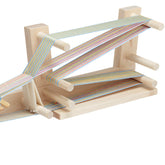 The Schacht Inkle Loom w/Belt Shuttle from Schacht Spindle Co. features colorful striped threads arranged in intricate patterns across multiple pegs on the frame. This portable loom consists of several horizontal and vertical wooden rods, creating varied angles for the weaving process.