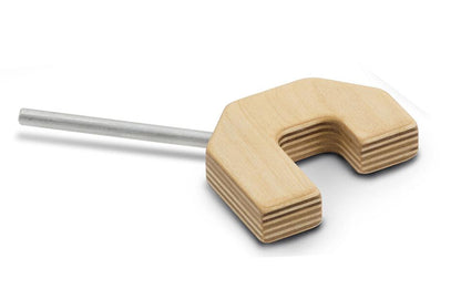 The Schacht Raddle U-Bracket by Schacht Spindle Co. features a wooden block with a U-shaped cutout and a smooth cylindrical metal rod extending from its side. The wood has a layered, laminated appearance, suggesting it is a tool or component for Wolf looms or similar loom accessories.